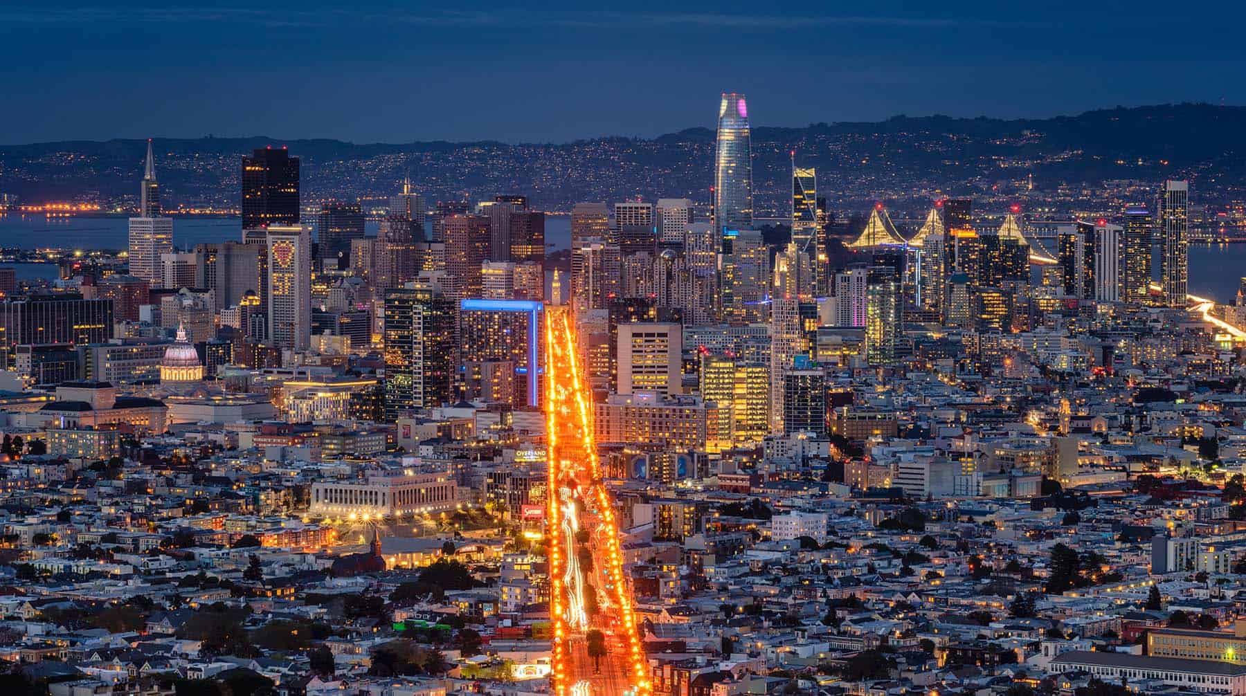 Skyline van San Francisco bij nacht met verlichte Market Street en Bay Bridge op de achtergrond